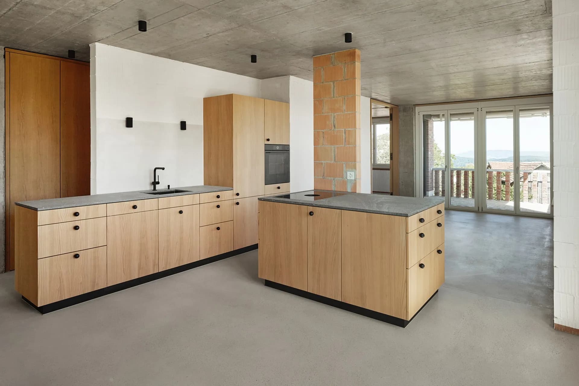 Wohnraum mit von Mion AG verlegtem fugenlosem Boden, Sichtbeton-Decke, Eichenholzküche, helle Atmosphäre